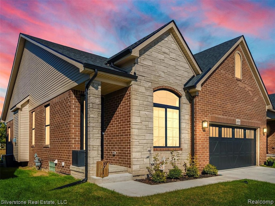 View of front of home featuring stone siding, a garage, and a shingled roof
