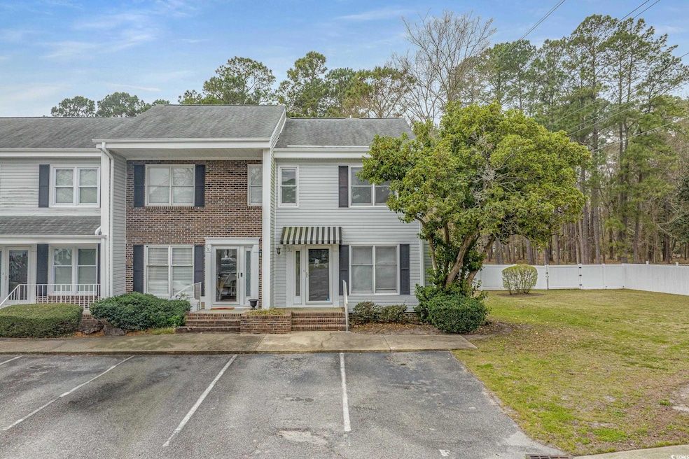 View of property featuring uncovered parking, a shingled roof, a front yard, and fence