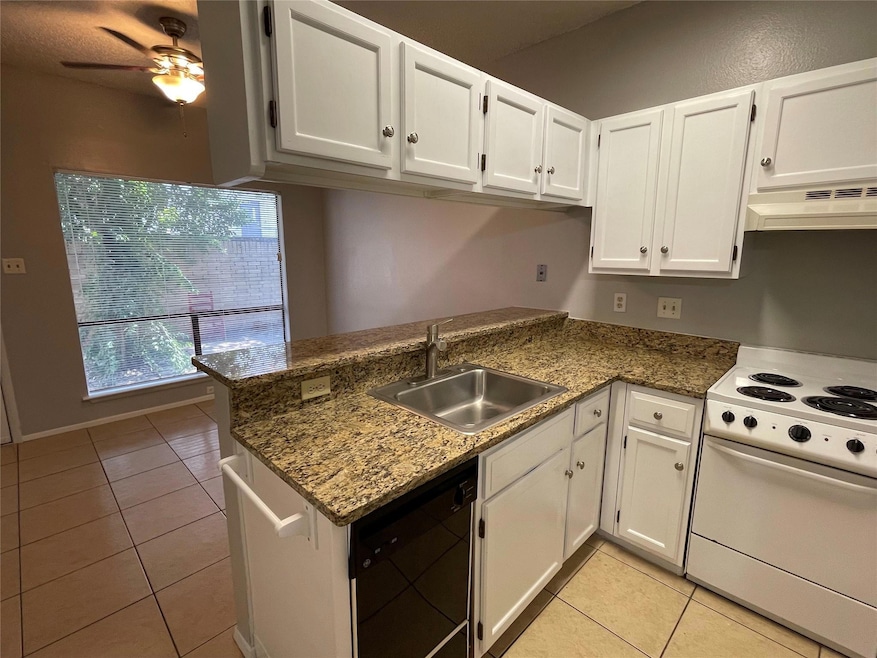 Kitchen featuring light tile patterned floors, white range with electric cooktop, white cabinets, a peninsula, and dishwasher