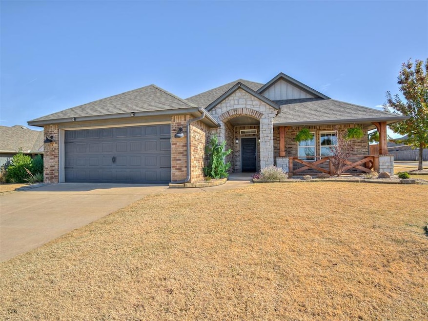 View of front of house featuring a shingled roof, brick siding, concrete driveway, a front yard, and covered porch