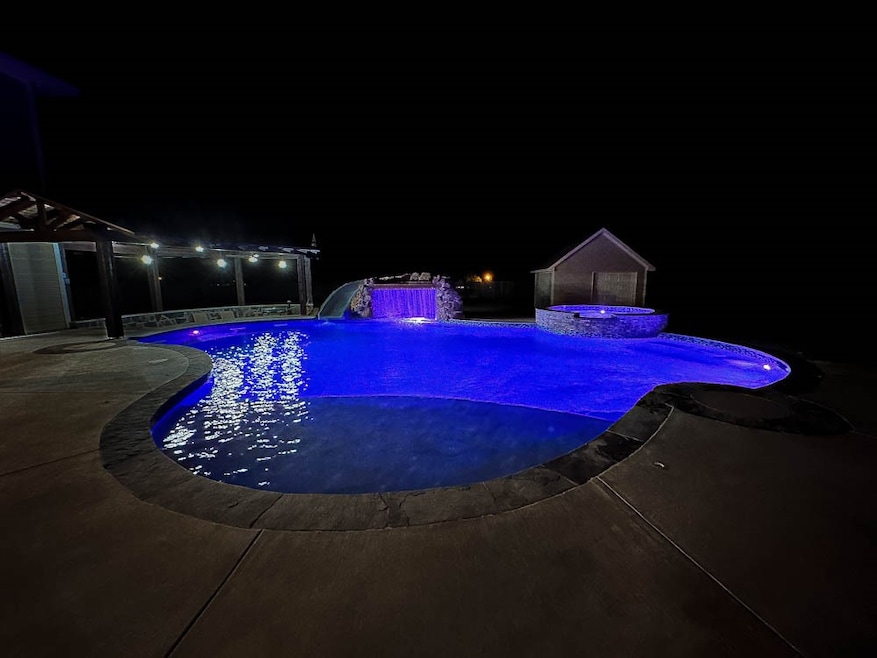 Pool at twilight featuring a patio area, a water slide, and a pool with connected hot tub