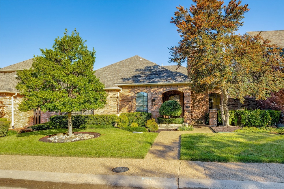 Traditional brick home with a landscaped front yard and mature trees.