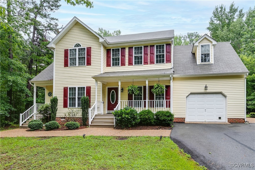 Charming two-story home with a welcoming front porch, classic red shutters, and a spacious attached garage — nestled on a quiet, wooded lot