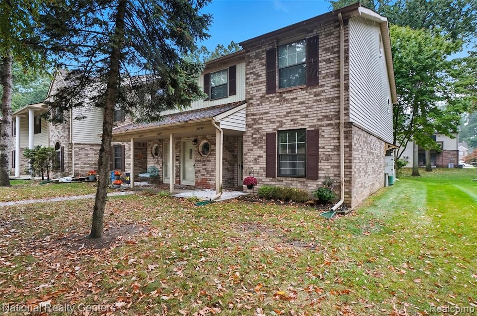 View of front of home with covered porch, a front yard, and brick siding