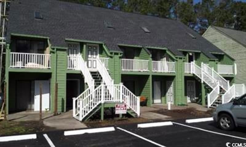 View of building exterior featuring stairway and uncovered parking