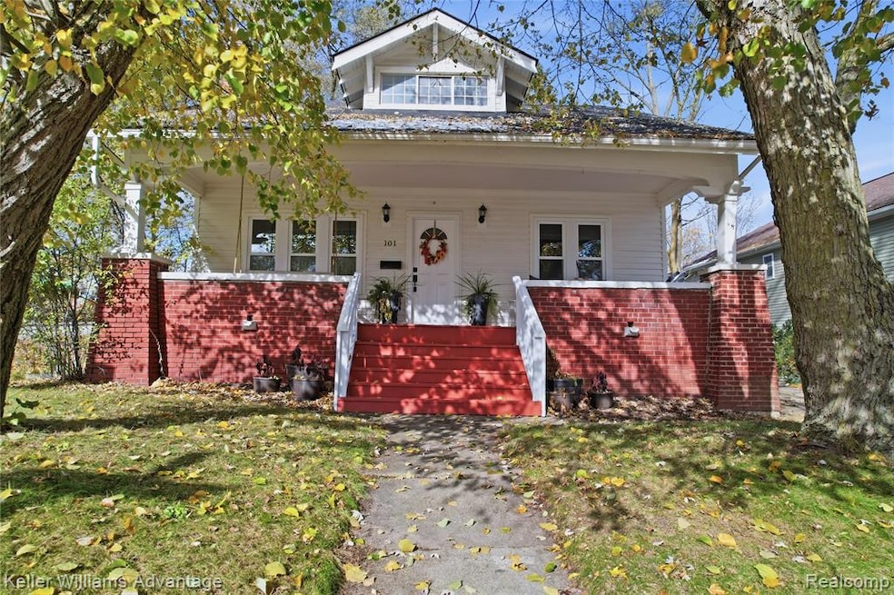 Bungalow with a porch, brick siding, a front yard, and stairs