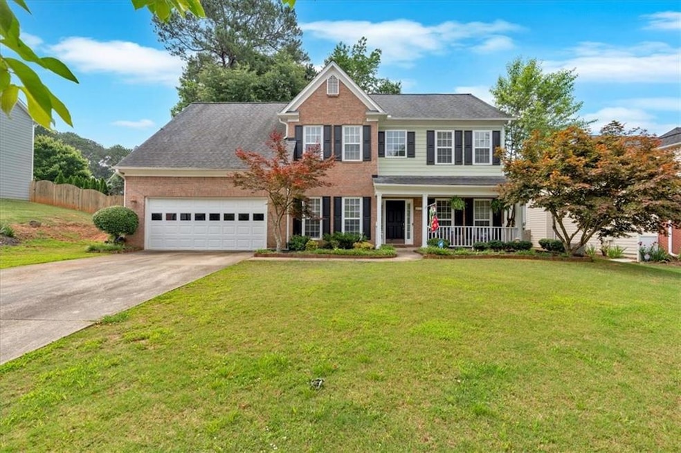 Colonial inspired home featuring a porch, an attached garage, driveway, and brick siding