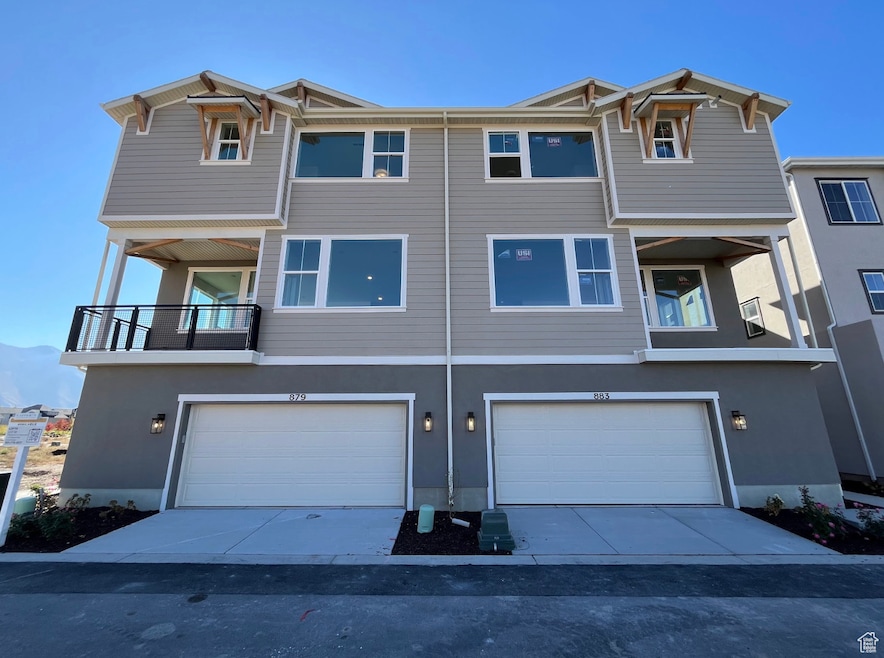 Traditional-style home with concrete driveway, stucco siding, a balcony, and an attached garage