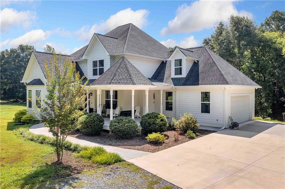View of front of home featuring roof with shingles, covered porch, an attached garage, and concrete driveway