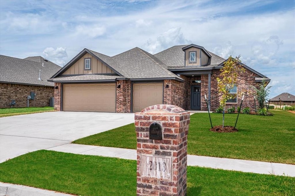 View of front of house featuring an attached garage, brick siding, a front yard, and concrete driveway