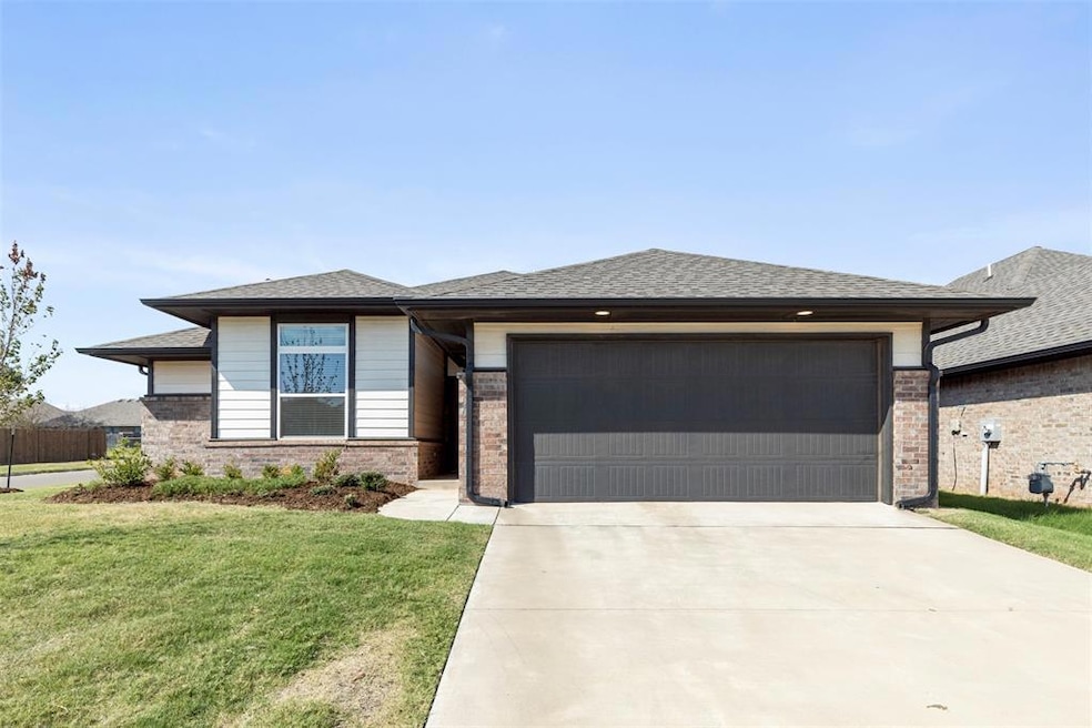 Prairie-style home with a front lawn, roof with shingles, concrete driveway, and brick siding