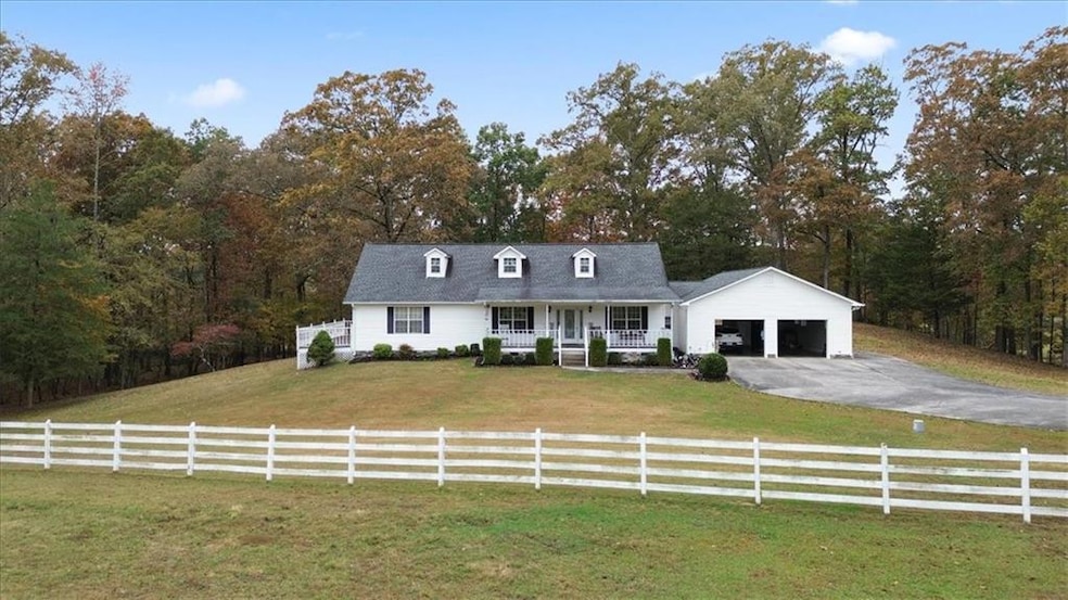 Cape cod home with covered porch, a front lawn, driveway, and a garage
