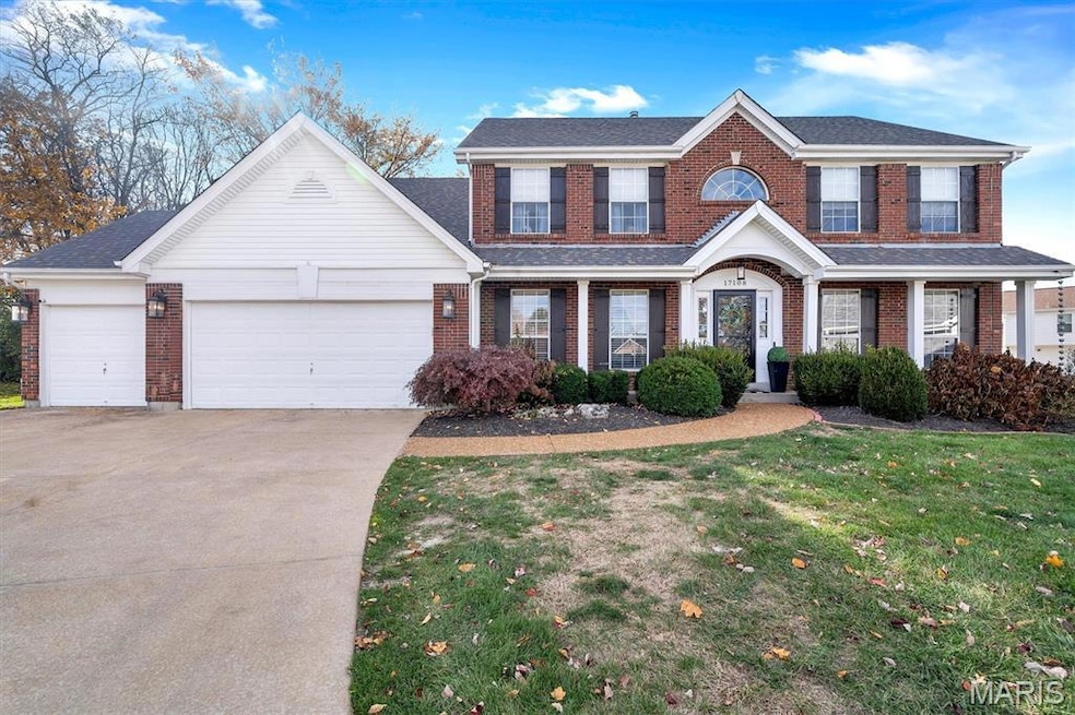 View of front of home featuring an attached garage, concrete driveway, a front yard, and brick siding