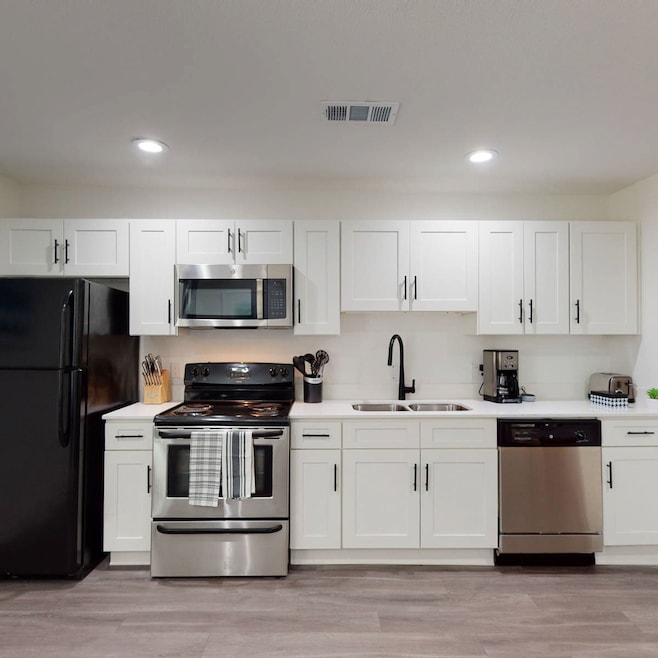 Kitchen with appliances with stainless steel finishes, white cabinetry, light wood-style flooring, and recessed lighting