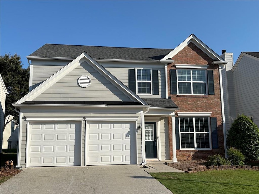 Traditional-style home with concrete driveway, bri