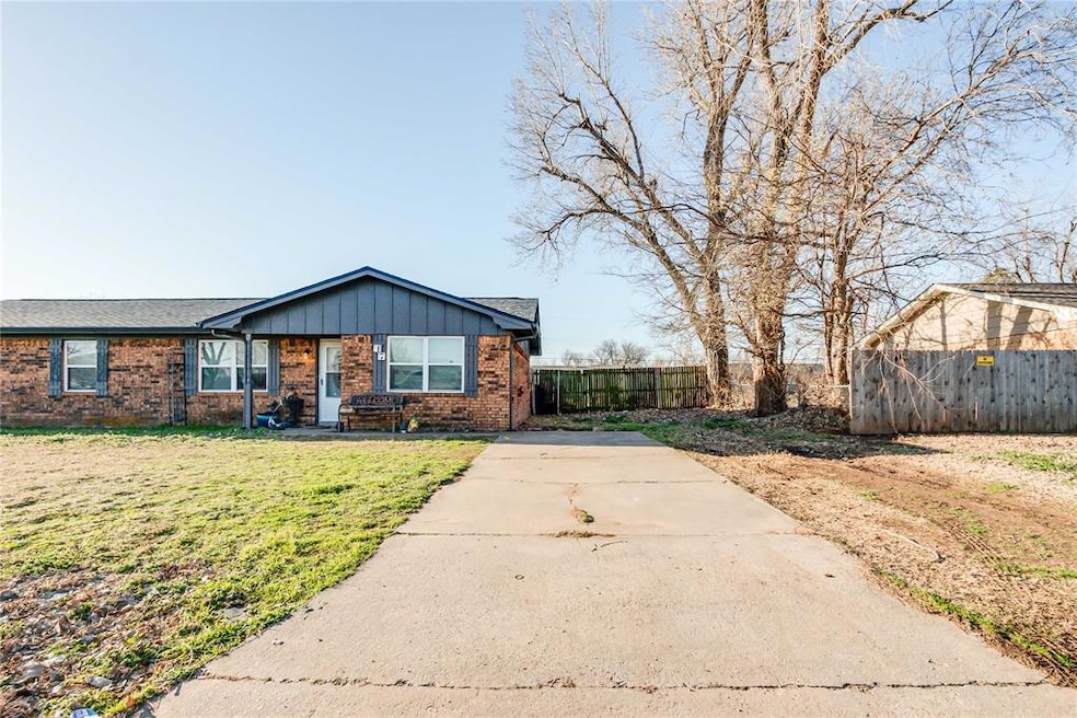 Single story home with brick siding, driveway, and board and batten siding