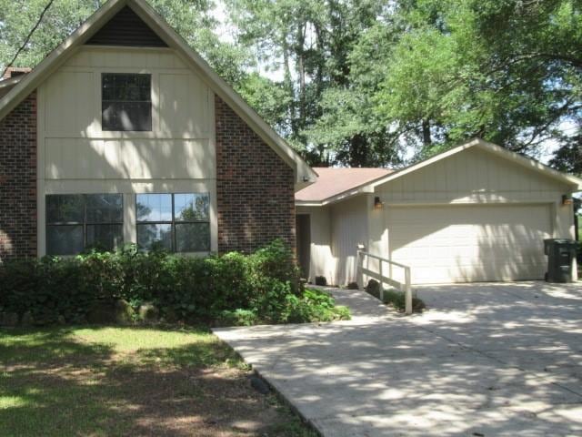 View of front of home with an attached garage, driveway, and brick siding