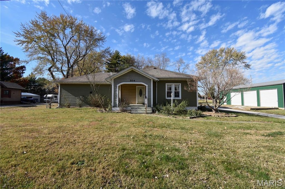 View of front of house with a porch, a front yard, an outbuilding, and a shingled roof