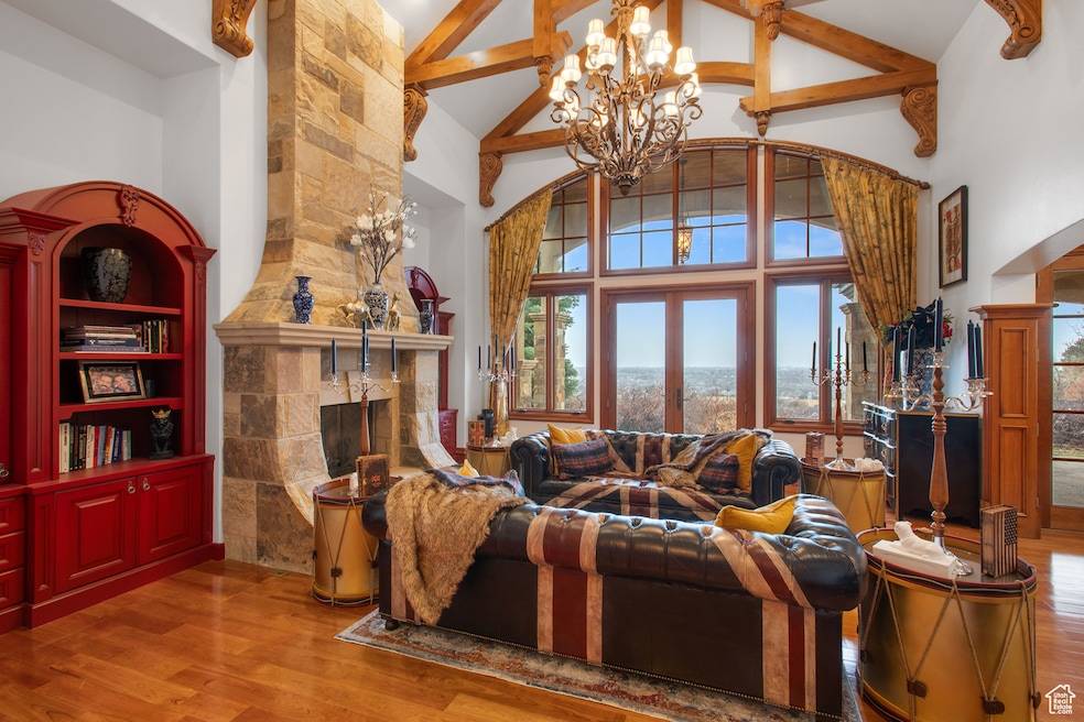 Living room featuring high vaulted ceiling, arched walkways, wood finished floors, a tile fireplace, and beamed ceiling