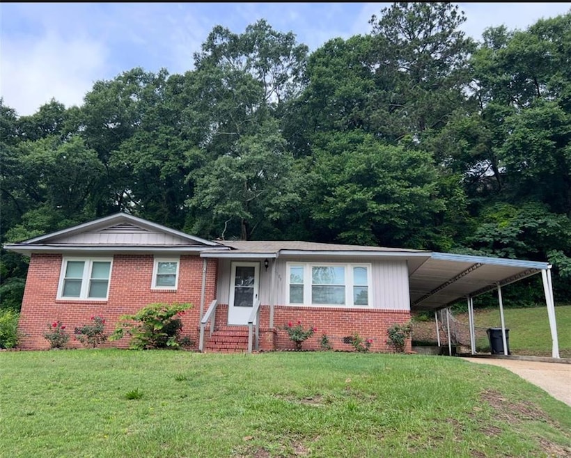 View of front of house with driveway, a front yard, brick siding, and an attached carport