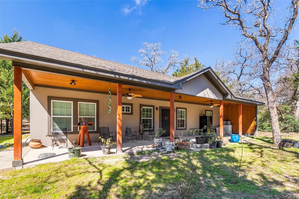 Back of house featuring a lawn, stucco siding, a 