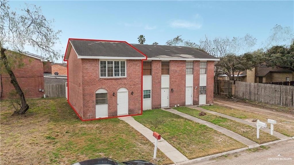Townhome / multi-family property with brick siding, fence, and a front lawn