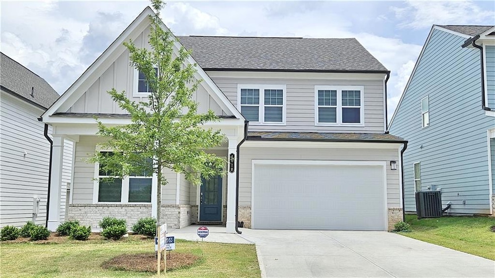 View of front of house with an attached garage, concrete driveway, a front yard, and roof with shingles