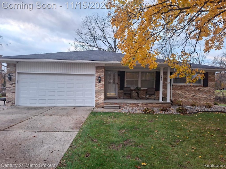 Ranch-style home featuring a front lawn, brick siding, concrete driveway, an attached garage, and a porch