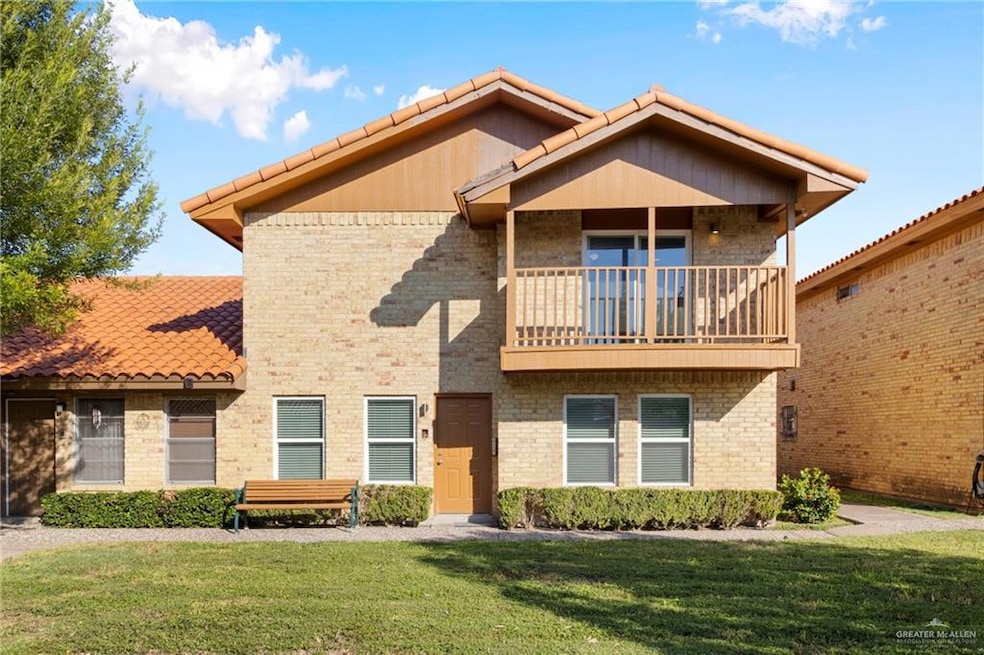 View of front of property with a front yard and a balcony