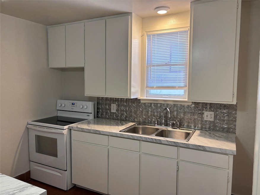 Kitchen featuring white cabinets, white electric r
