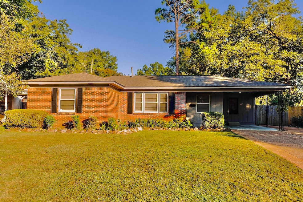 Ranch-style home featuring a carport and a front y