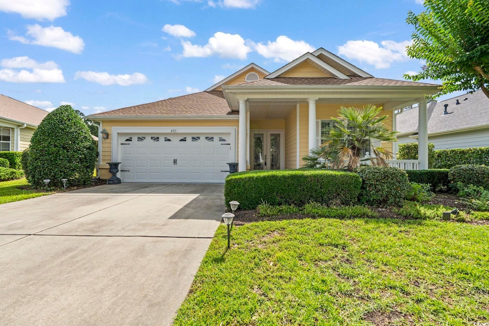 View of front facade featuring a garage, concrete driveway, french doors, and a front lawn