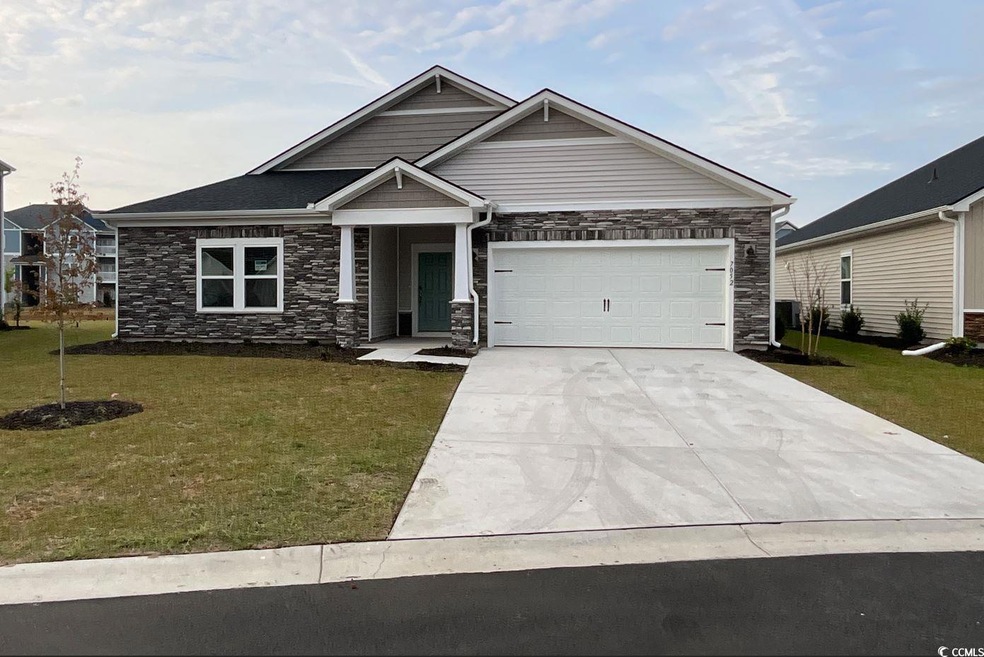 Craftsman-style house with stone siding, driveway, and a front lawn