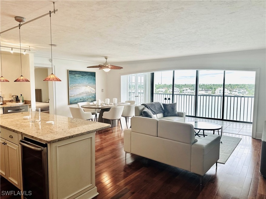 Living room featuring dark wood-type flooring, a water view, a textured ceiling, and a ceiling fan