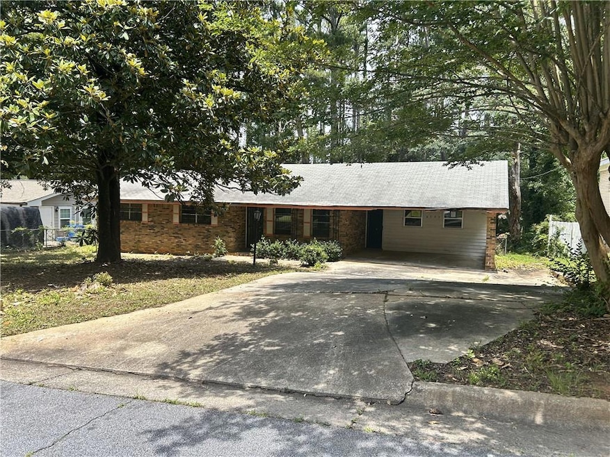 Ranch-style house featuring concrete driveway and an attached carport