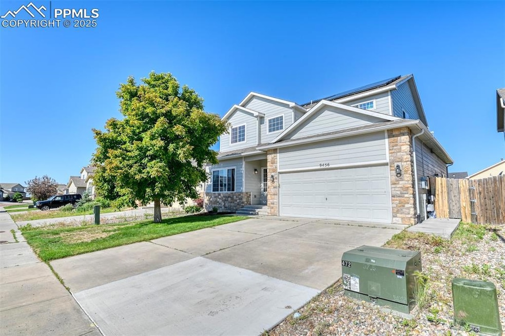 View of front facade featuring stone siding, driveway, and an attached garage