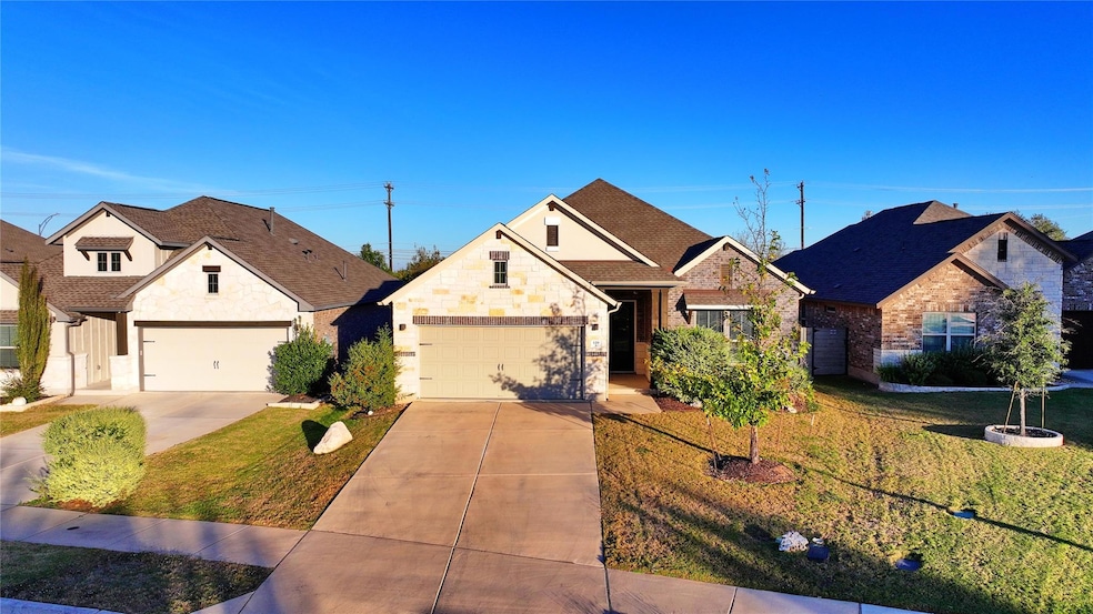 View of front of house with a front lawn, driveway, stone siding, a shingled roof, and a garage