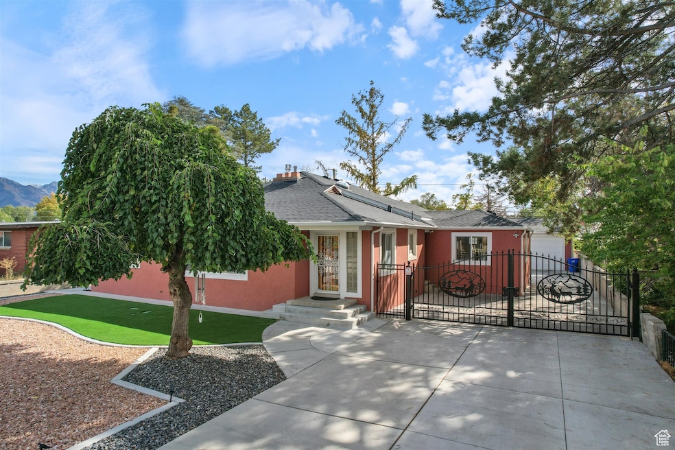 View of front of home featuring a shingled roof, a chimney, stucco siding, and a gate