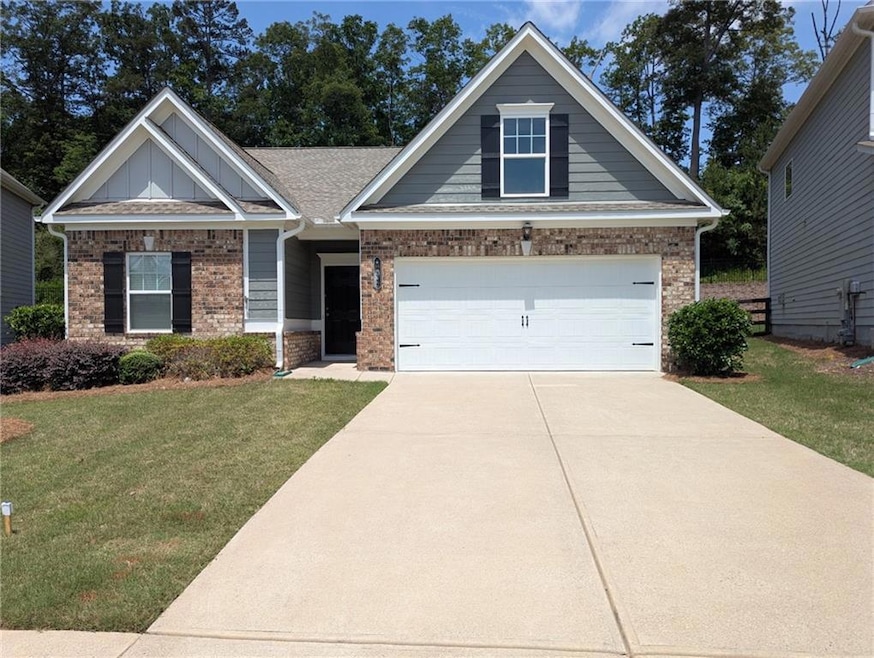 Craftsman house featuring brick siding, a front yard, driveway, and board and batten siding
