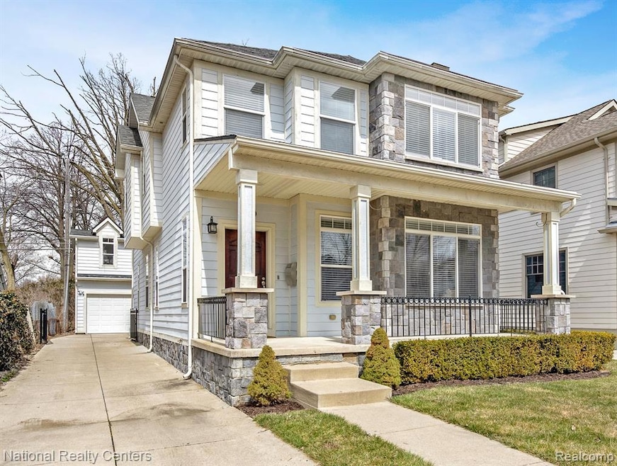 View of front facade featuring a porch, stone siding, a garage, and driveway