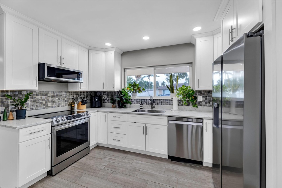 Kitchen is updated with white shaker cabinets, sta