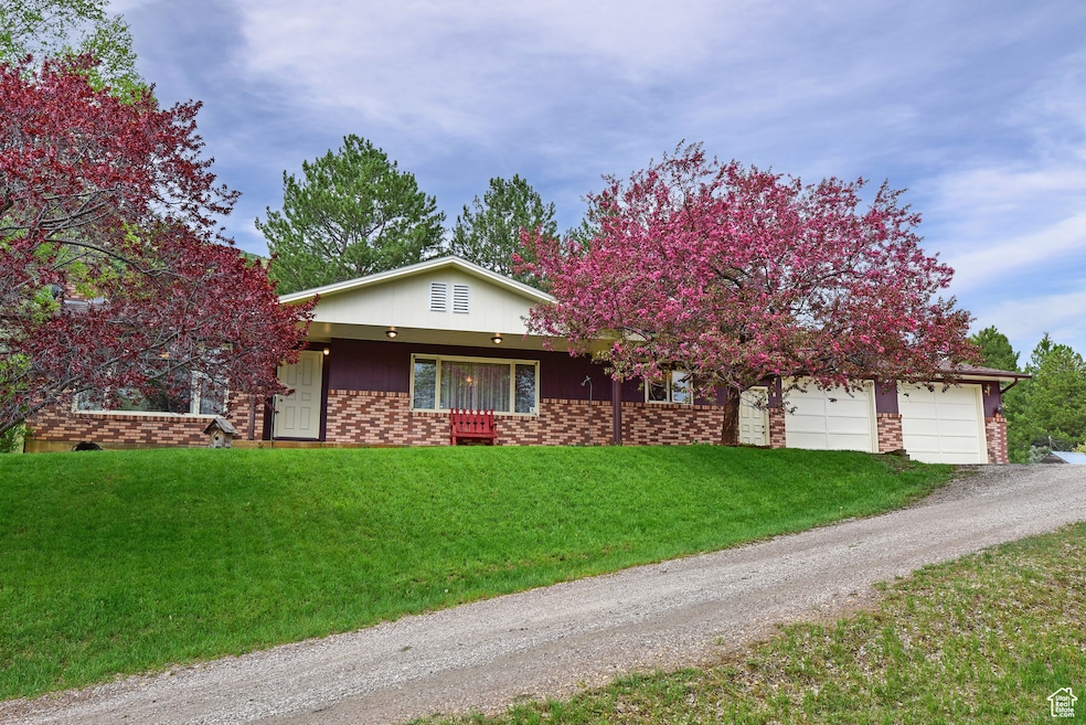 View of front of house with gravel driveway, a front lawn, brick siding, and an attached garage