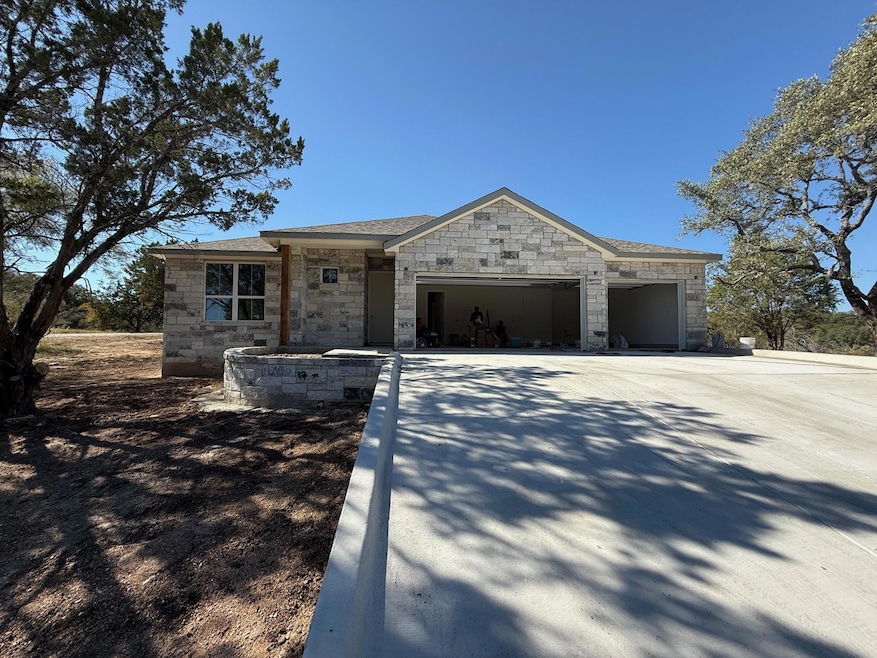 View of front of house featuring stone siding, concrete driveway, and a garage