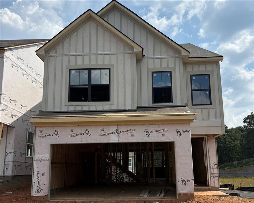 View of front facade with board and batten siding, a shingled roof, and a garage