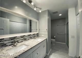 Master bathroom featuring double vanity, backsplash, a closet, and a shower with shower door