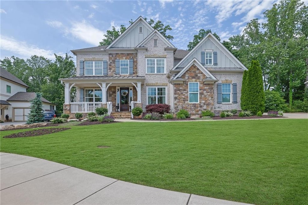 Craftsman inspired home with board and batten siding, a porch, a front yard, stone siding, and a standing seam roof