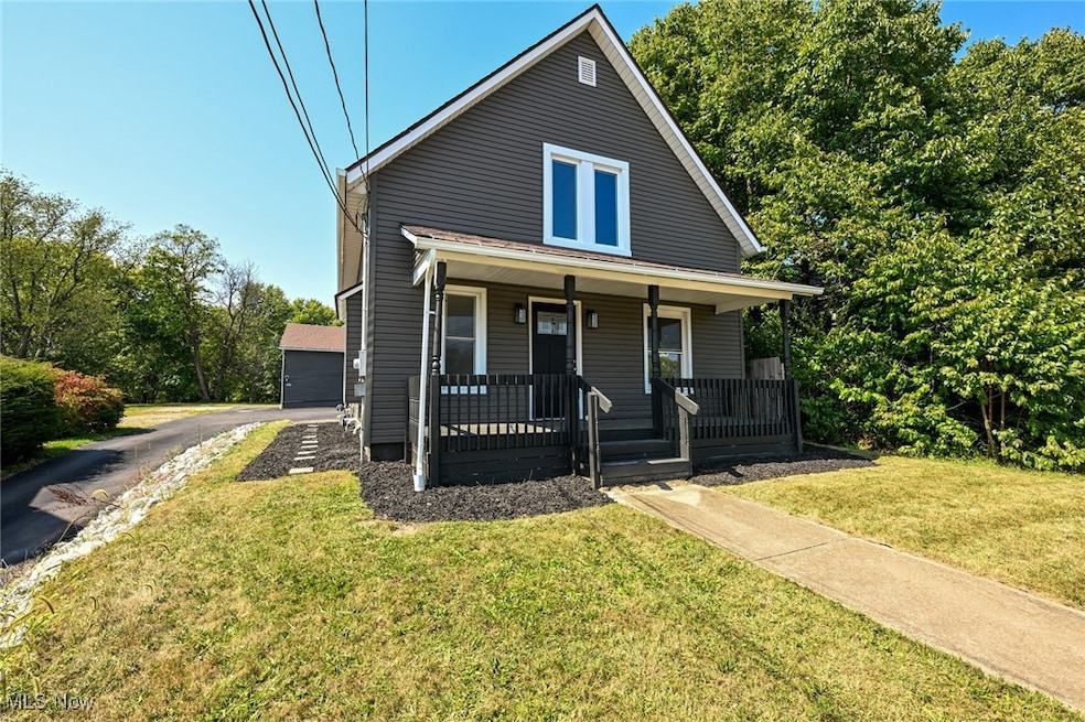View of front of house with covered porch, a front yard, and a garage