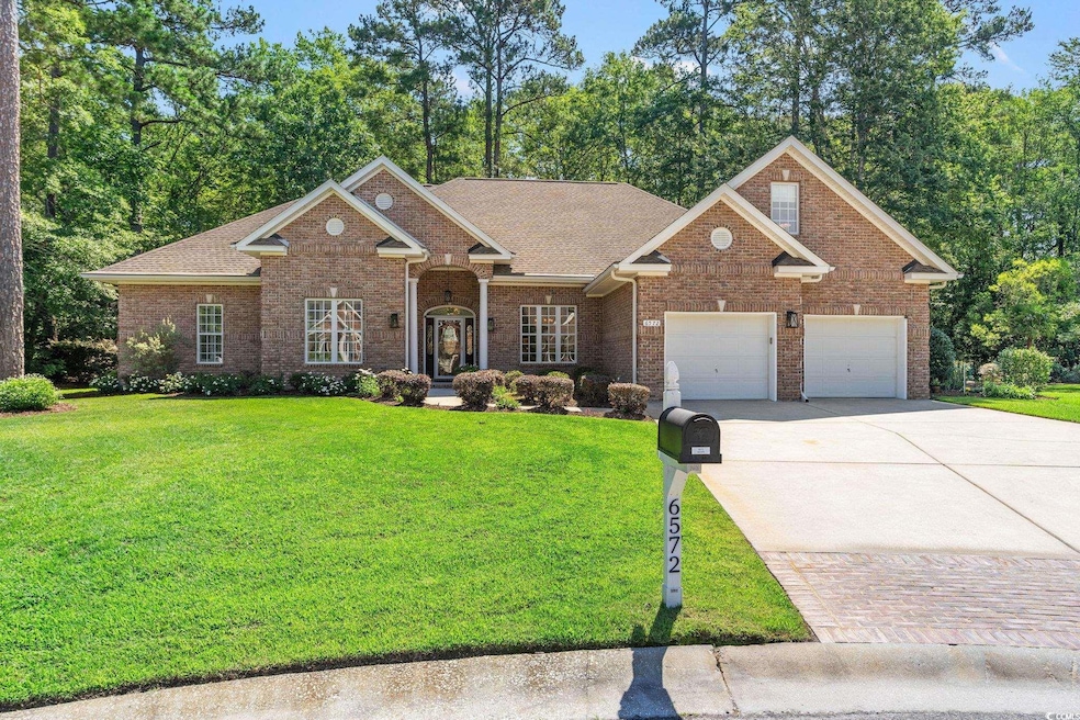 View of front of house featuring driveway, a front yard, an attached garage, and brick siding