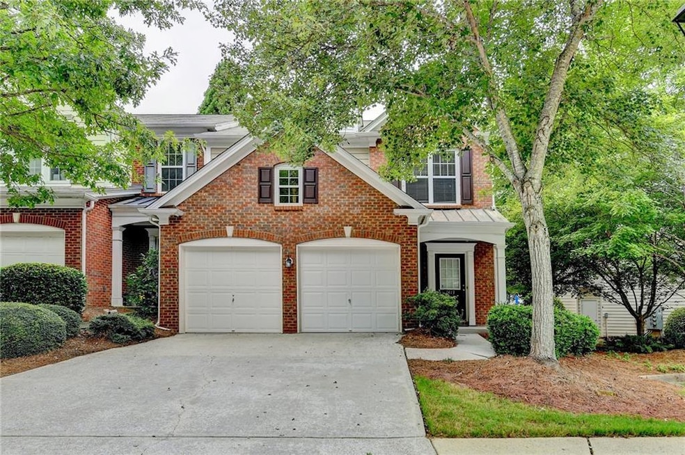 Traditional-style home featuring concrete driveway, brick siding, an attached garage, and a standing seam roof