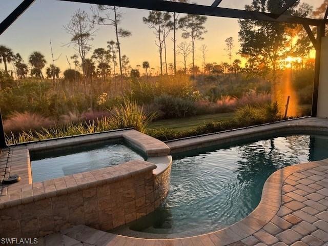 View of swimming pool featuring a pool with connected hot tub and glass enclosure